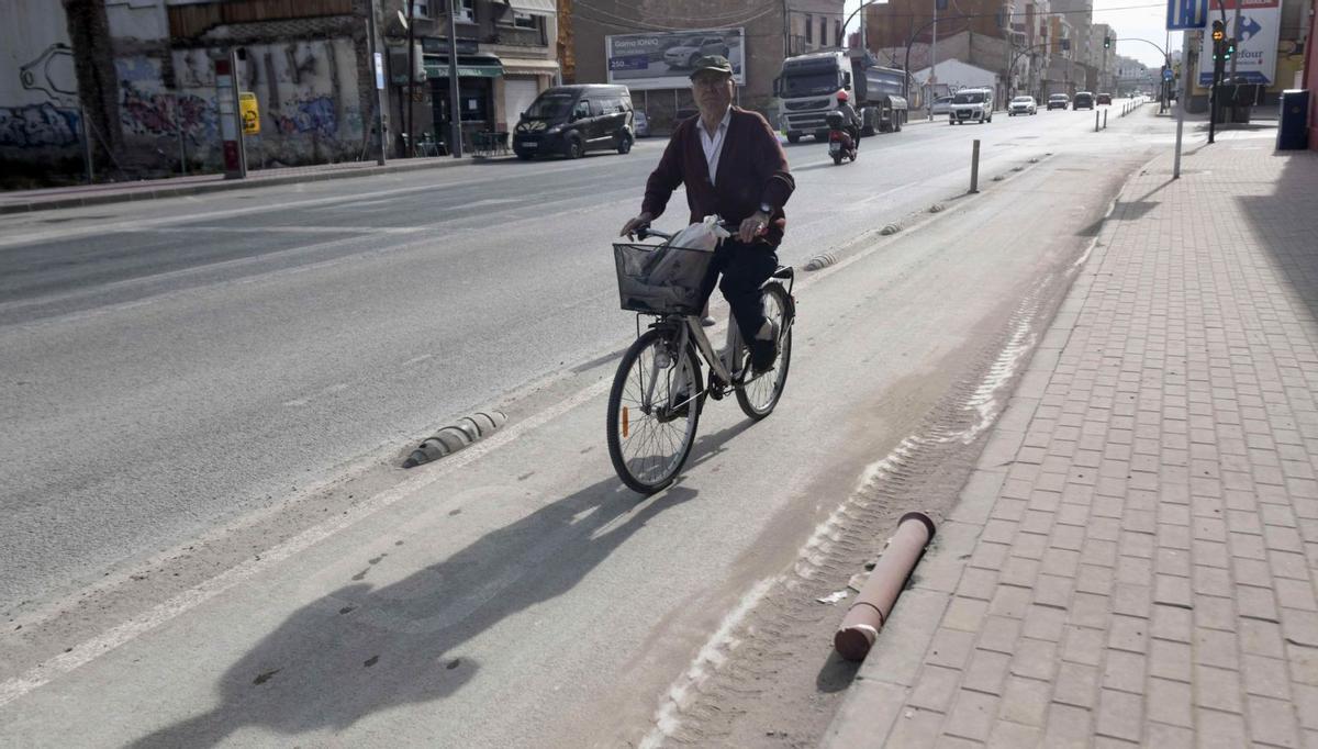 Un ciclista pasa por el actual carril bici, con señales semiborradas.
