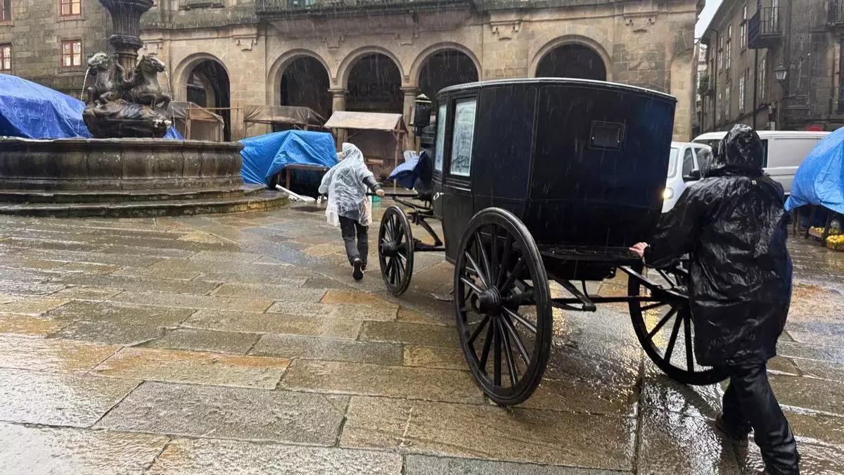 Varios operarios mueven un carruaje de época en la compostelana Praza das Pratarías durante la grabación de la serie