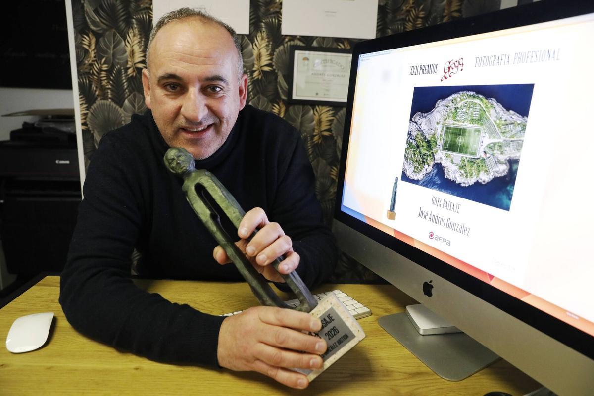 Andrés González con su estatuilla del premio Goya de fotografía con la imagen ganadora en la categoría de Paisaje en la pantalla de su ordenador.