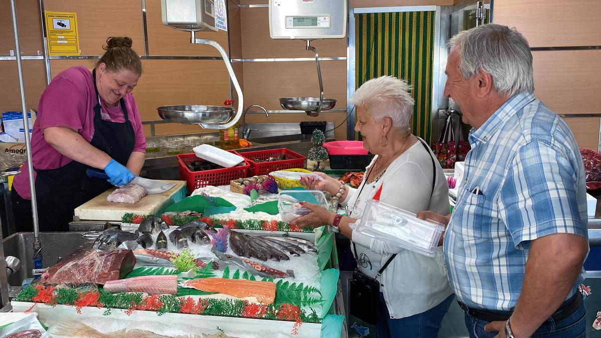 Dos clients comprant en una peixateria de la Seu d&#039;Urgell amb les carmanyoles preparades per endur-se el peix que han adquirit