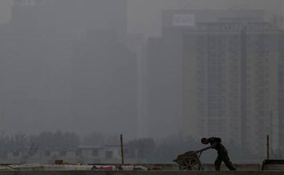 Un treballador de la construcció empeny un carret durant un dia ennuvolat a prop del districte central de Pequín (Xina).