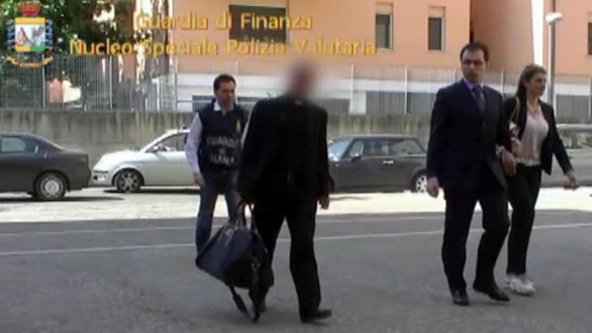 Agentes de la policía fiscal acompañan al prelado Nunzio Scarano, tras su detención el viernes.