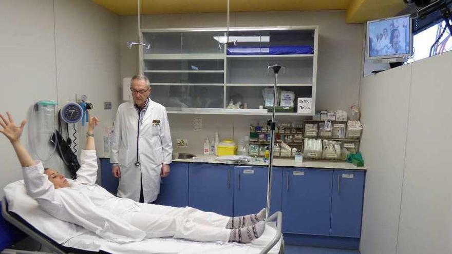 Una paciente realiza los movimientos que le ordena por la pantalla (arriba, a la derecha) el especialista del HUCA durante la simulación, ante la mirada del doctor Ignacio Cortina, ayer, en Cangas del Narcea.