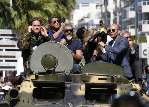 Cast members Sylvester Stallone, Mel Gibson, Jason Statham and Harrison Ford pose on a tank as they arrive on the Croisette to promote the film "The Expendables 3" during the 67th Cannes Film Festival in Cannes