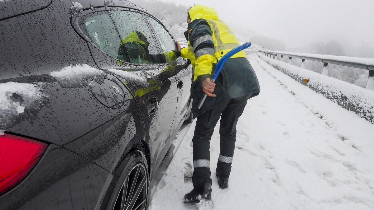 Un Guardia Civil auxilia a un conductor atrapado por la nieve en la A-6