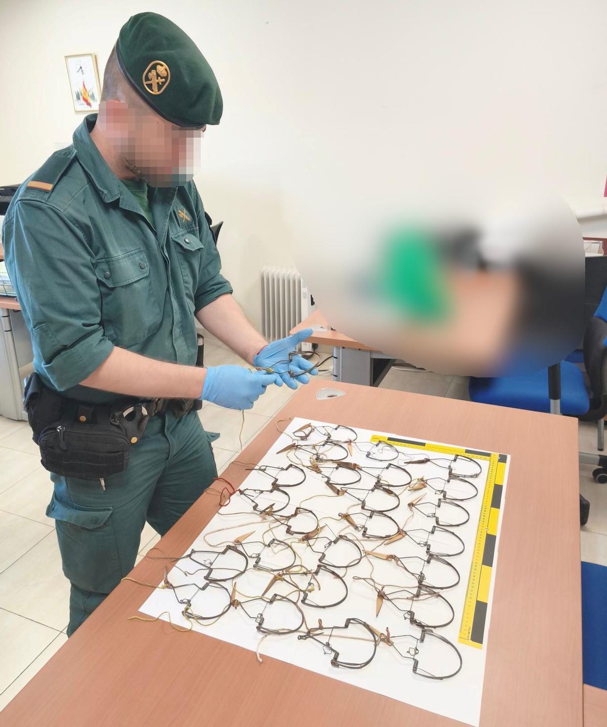 Un agente de la Guardia Civil observa las trampas intervenidas.