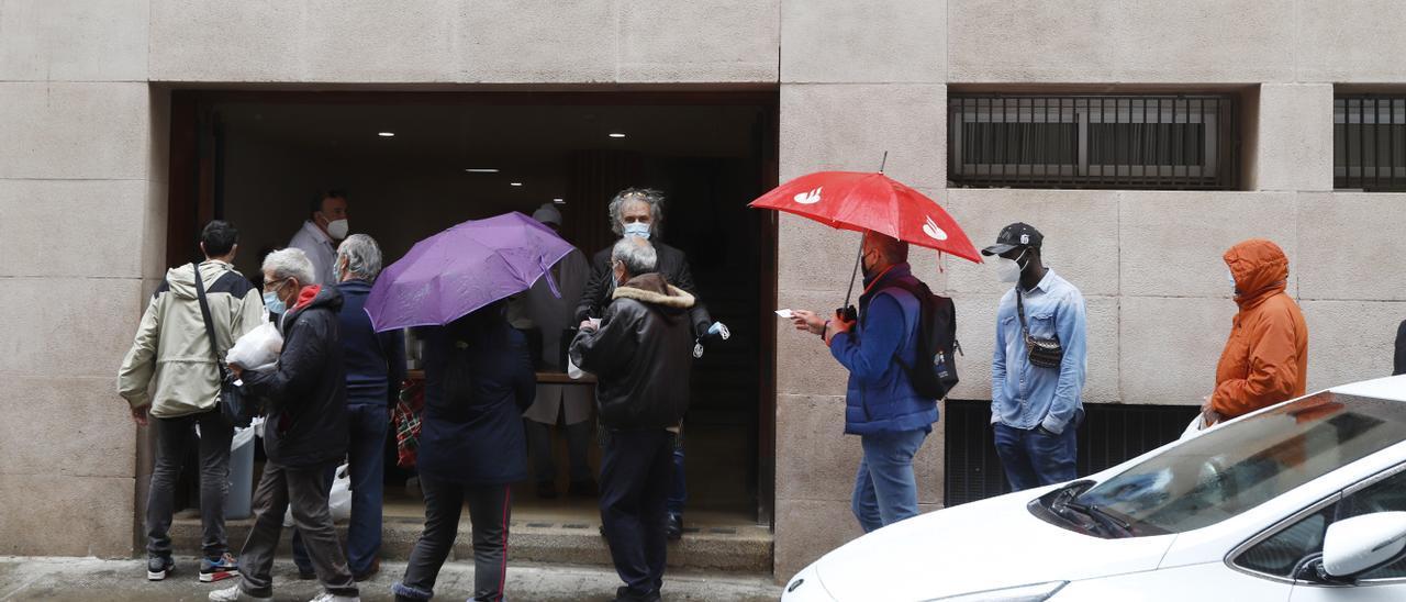 Los transeúntes pasan, ayer, por la puerta del comedor social de la parroquia del Carmen a recoger bolsas con comida.