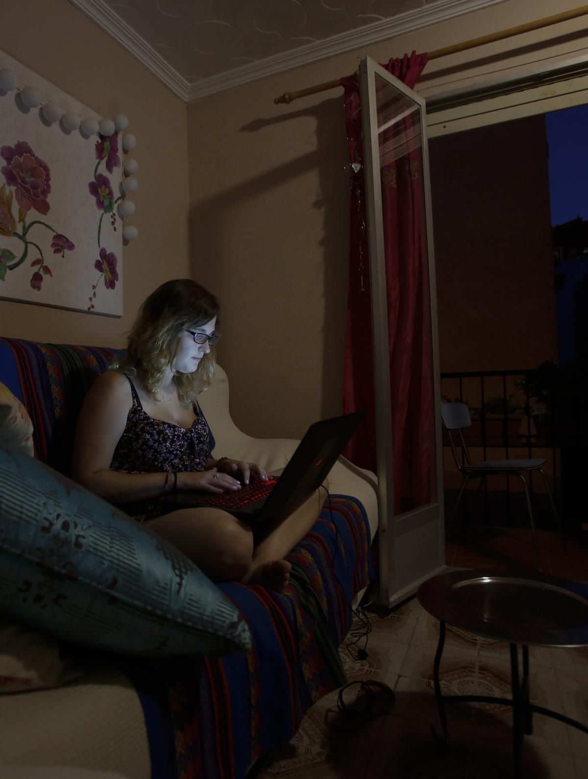 Una joven con su ordenador en el comedor de una casa.