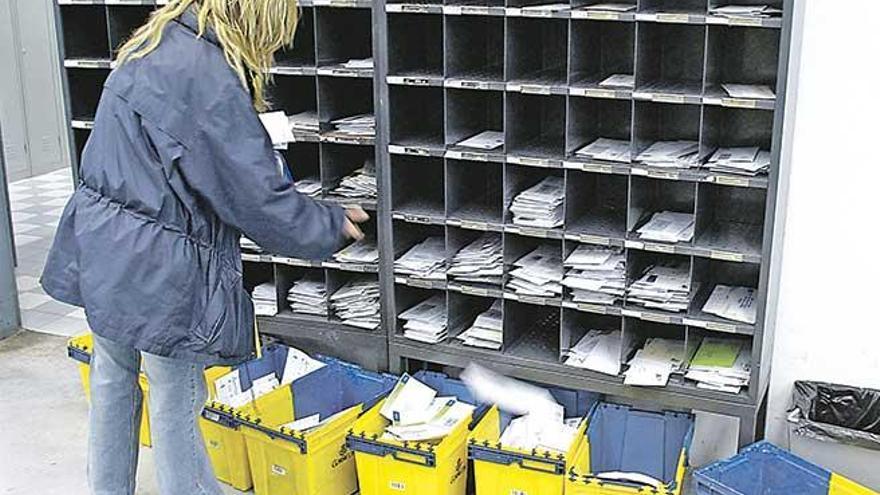 Una trabajadora de Correos distribuye la correspondencia en una oficina postal.