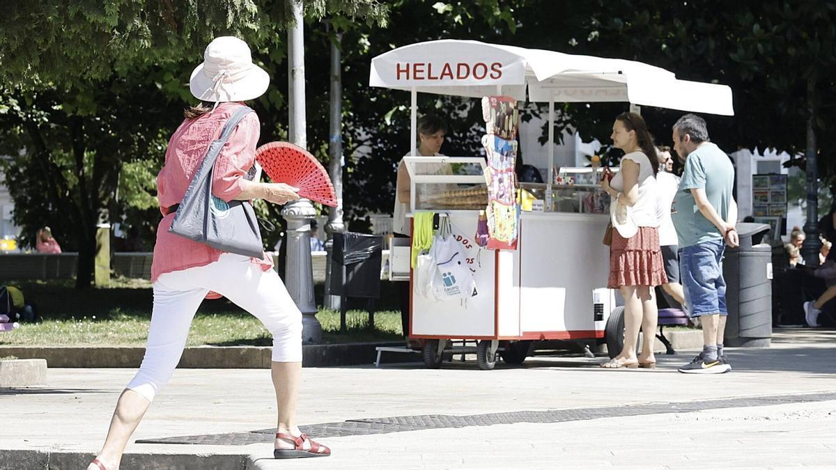 Una mujer con un abanico frente a un puesto de helados.