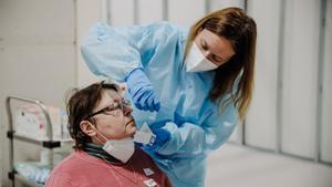 Archivo - Una sanitaria realiza pruebas Covid a personas refugiadas, a su llegada al Hospital Isabel Zendal, a 16 de marzo de 2022