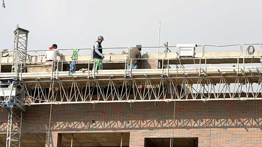 Un grupo de operarios de la construcción trabaja en la cubierta de un edificio de viviendas en Alicante.