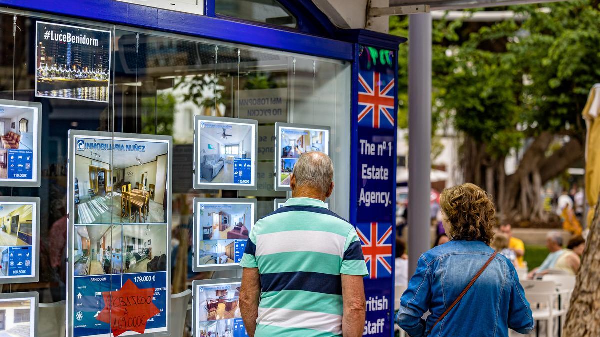 Una pareja mira las ofertas de apartamentos en una inmobiliaria de Benidorm.