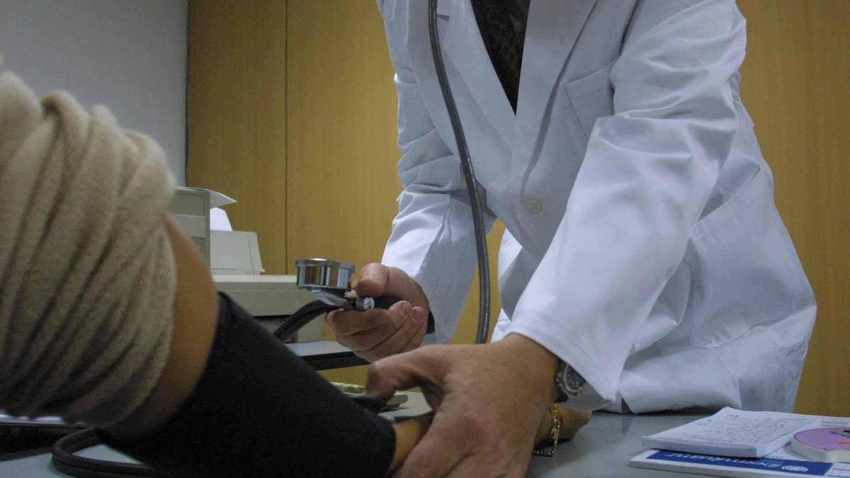 Un médico mide la tensión a un paciente
