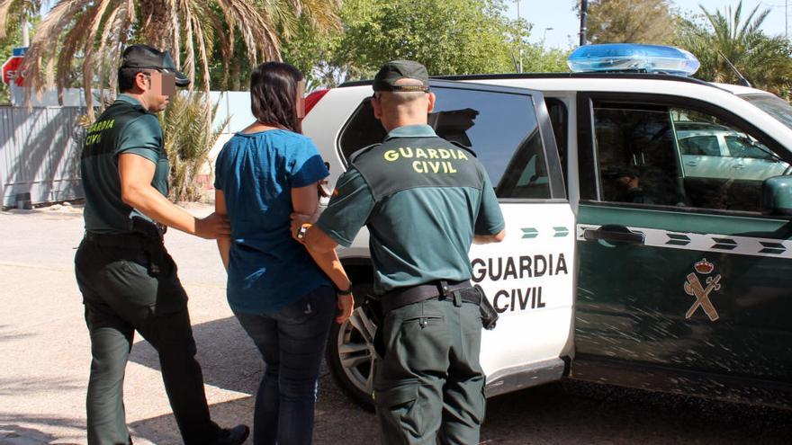 Dos guardias civiles conducen a una de las detenidas en la operación Tributo al interior de un furgón policial.