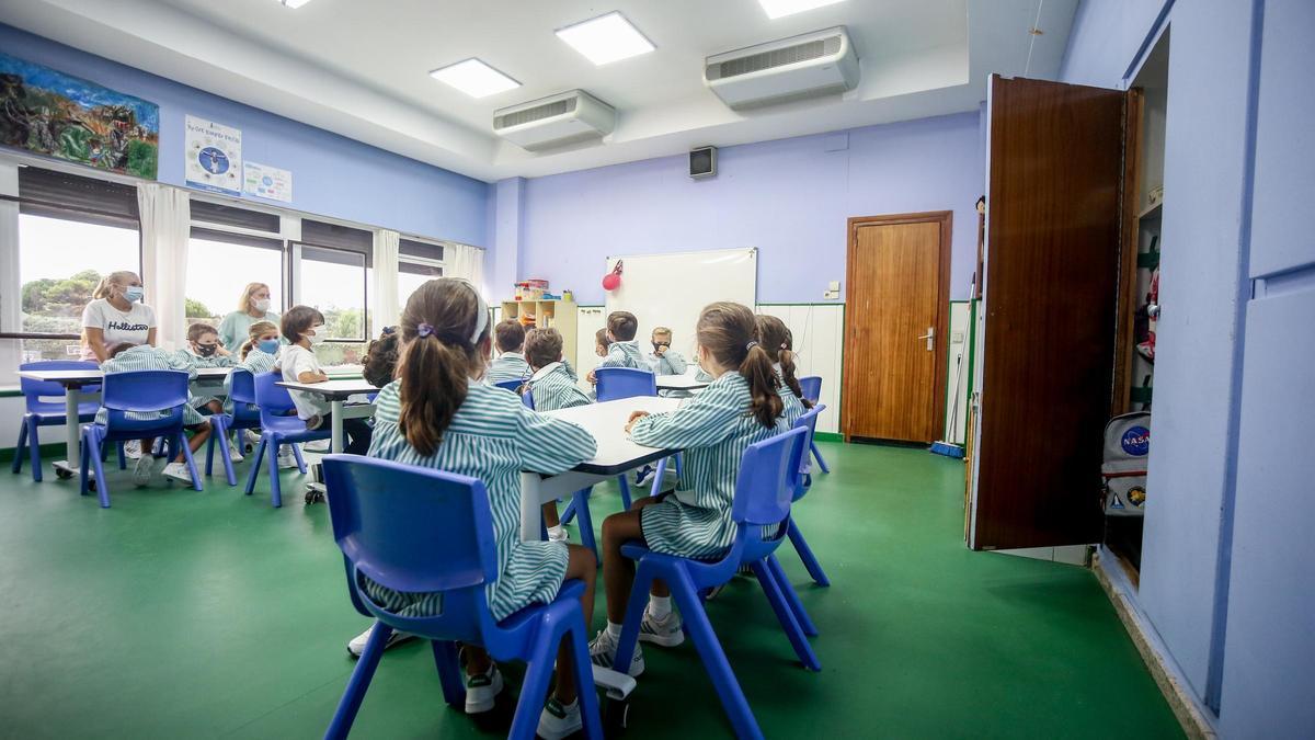 Varios niños sentados en pupitres en una clase.