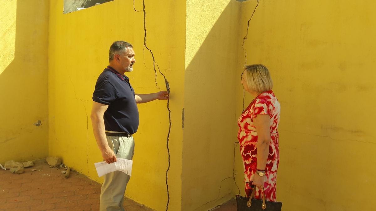 Ángel Meca e Isabel Navarro contemplan las grietas de la pared trasera de una vivienda.