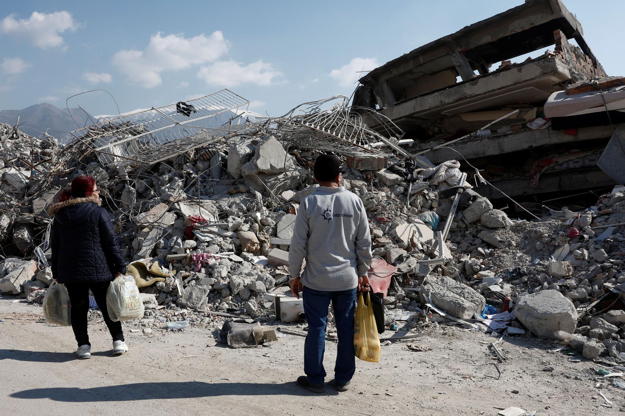 Dos habitantes de Alejandreta observan un edificio derrumbado por el terremoto.