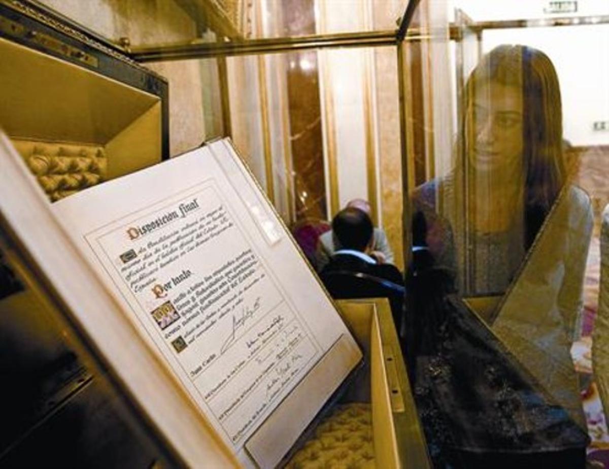 Una empleada del Congreso de los Diputados contempla el ejemplar único del texto original de la Constitución. 