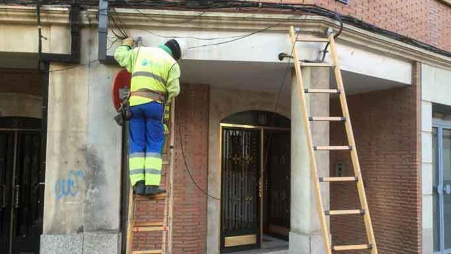 Un trabajador coloca cable de fibra en la fachada de un edificio próximo a la iglesia de San Juan.