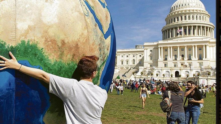 Un activista sostiene una bola del mundo frente al Capitolio.. // Faro