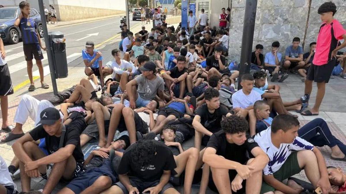 Menores migrantes esperan para su filiación frente a la Jefatura Superior de la Policía Nacional en Ceuta.