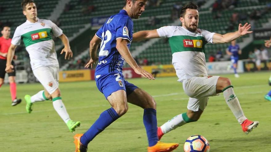 Linares controla el balón con el pecho en el área del Elche marcado por Túñez.