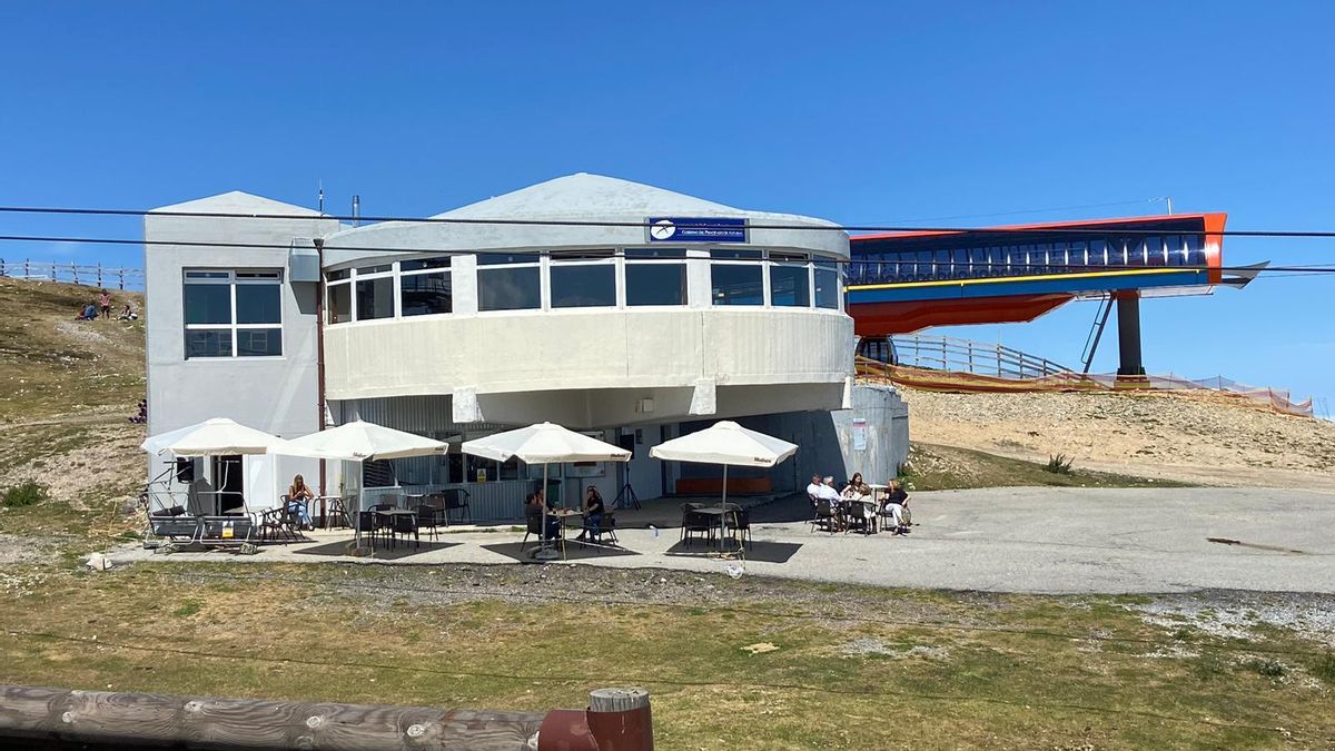 Turistas en la terraza de la cafetería de la cota alta de Pajares con la telecabina al fondo.