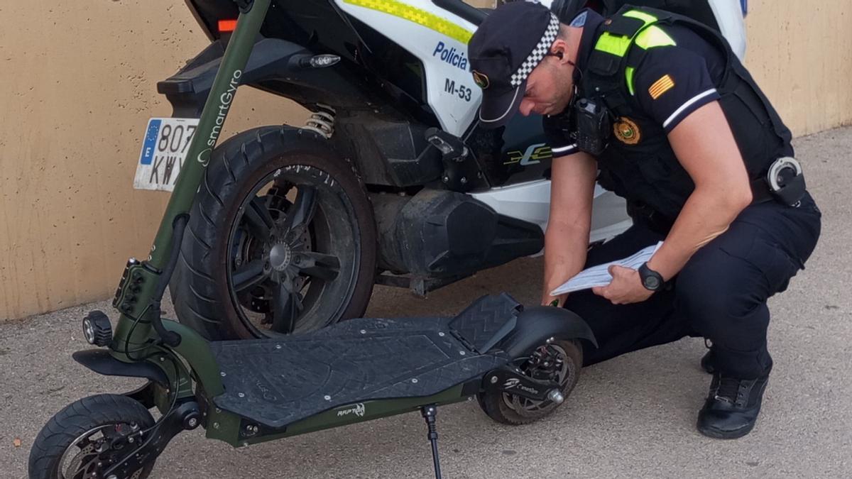 Un agente de la Policia Local de Santa Coloma revisa un patinete eléctrico