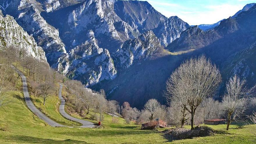 Tramo de la carretera de acceso a Casielles, con la montaña al fondo y algunas cabañas, a finales de marzo.