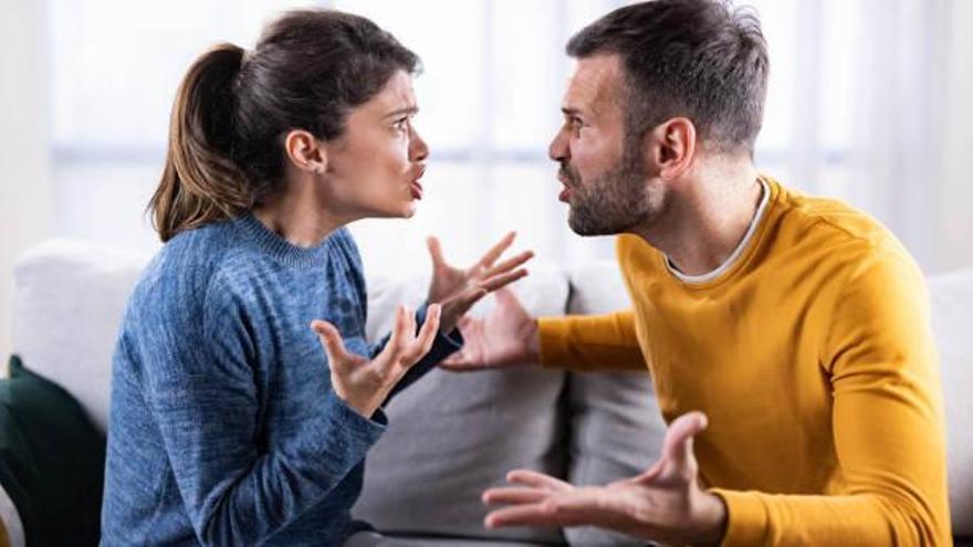 Una pareja discutiendo en el sofá de casa.