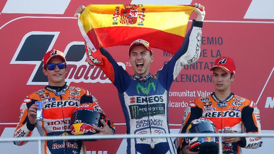 Lorenzo festeja, flanqueado por Márquez y Pedrosa, el triunfo en Cheste y su tercer título mundial en MotoGP.