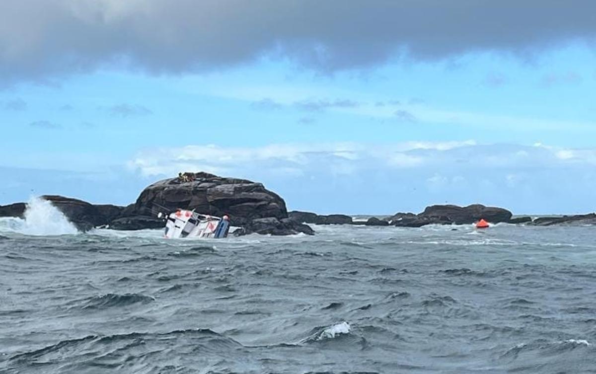 Imagen del momento del naufragio en la que se aprecia a los tripulantes sobre las rocas ya a salvo