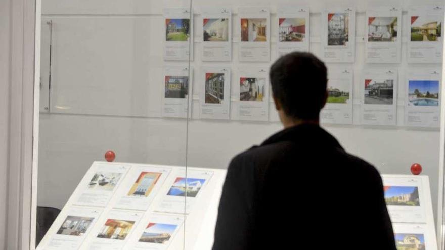 Un hombre observa ofertas de viviendas en una agencia inmobiliaria.