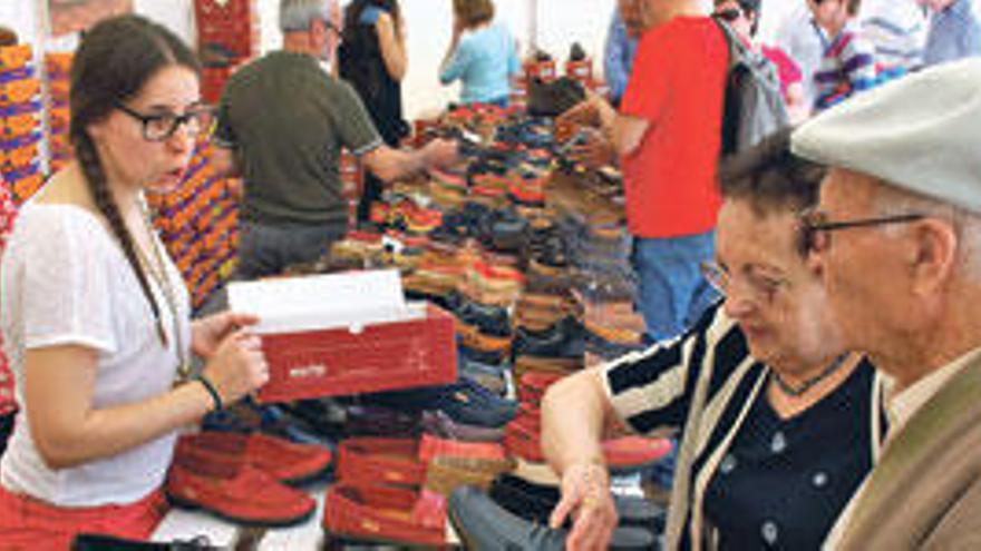 Una vendedora de calzado muestra un par de zapatos de calidad a una pareja de visitantes a la feria.