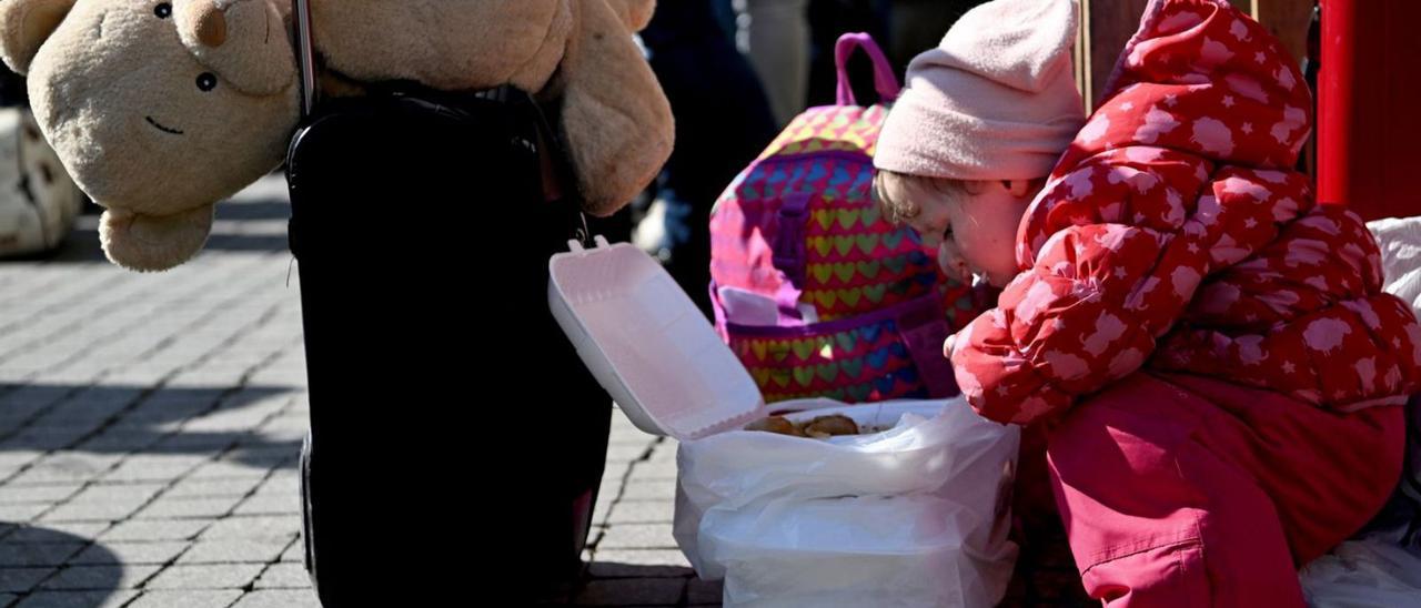 Una niña refugiada busca alimento en una bolsa entre sus enseres en Przemysl (Polonia).