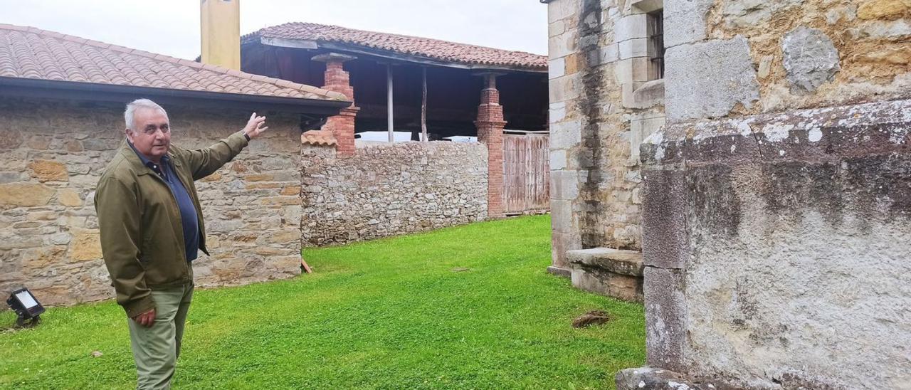 Emilio Pérez Cueva, señalando el tejado de la panera afectada por las filtraciones de las aguas pluviales de la iglesia prerrománica de Santianes de Pravia. | S. Arias