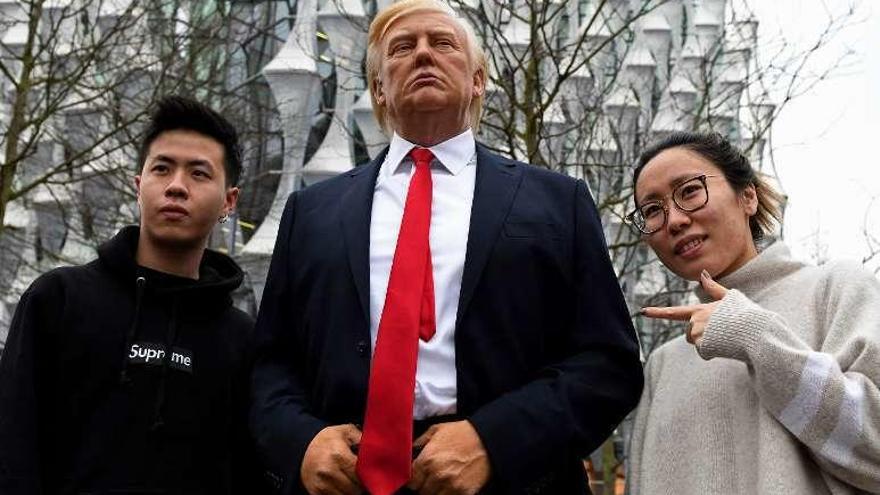 Dos turistas junto a una figura de cera de Trump en Londres. // AFP