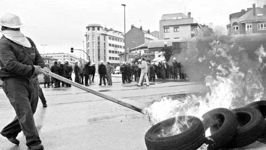 Un trabajador de Naval Gijón atiza la barricada que ayer colocaron en la plaza del Padre Máximo González.