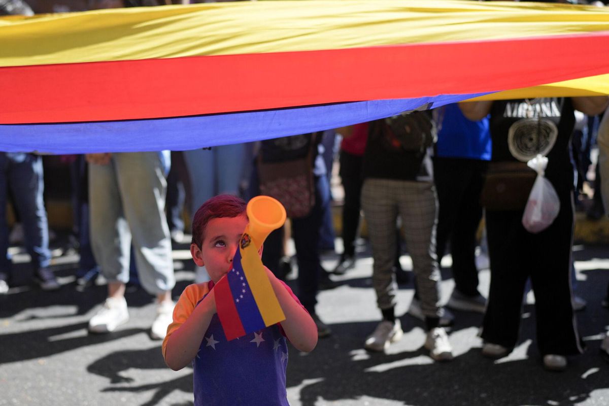 A youth plays a horn during a protest by opponents of Venezuelan President Nicolas Maduro the day before his inauguration for a third term in Caracas, Venezuela, Thursday, Jan. 9, 2025. (AP Photo/Matias Delacroix). EDITORIAL USE ONLY / ONLY ITALY AND SPAIN