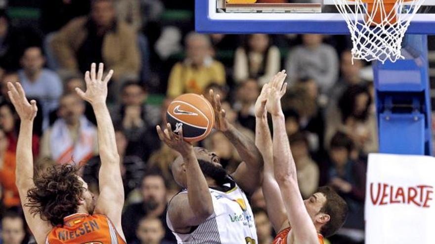 El pívot estadounidense del ViveMenorca Bud Eley (c) trata de anotar ante la defensa de los jugadores del Pamesa Valencia el pívot Albert Miralles (d) y el ala-pívot australiano Matt Nielsen, durante el partido correspondiente a la 22  jornada de la Liga ACB jugado este mediodía en el Pabellón de la Fuente de San Luis de Valencia. EFE/Manuel Bruque.