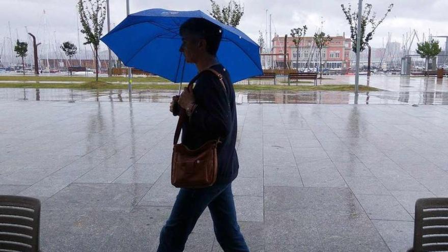 Una mujer pasea bajo la lluvia en la Marina.