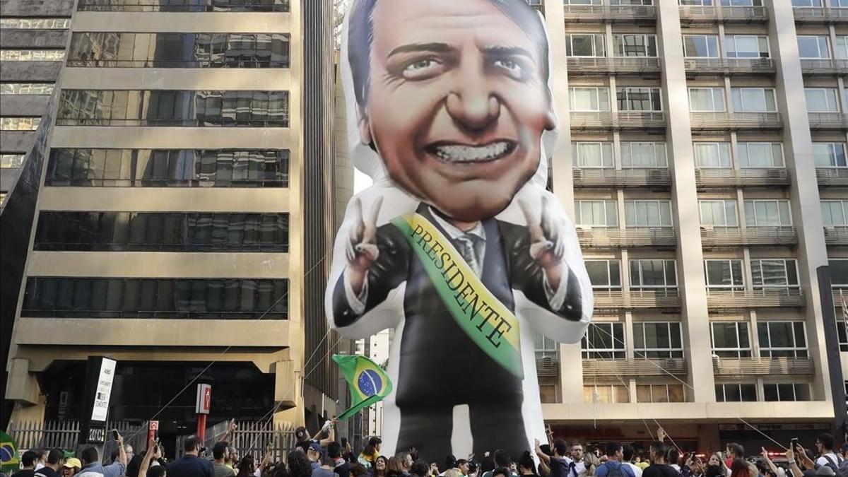 Simpatizantes del candidato Jair Bolsonaro exhiben una pancarta con un retrato del dirigente en la avenida Paulista, en Sao Paulo, el pasado septiembre.