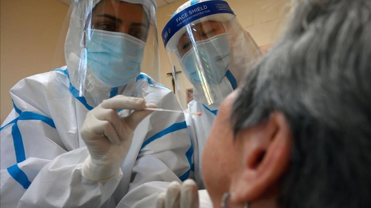 Trabajadores sanitarios hacen un test de coronavirus a uno de los ingresados en la residencia de ancianos Sant Miquel, en Barcelona