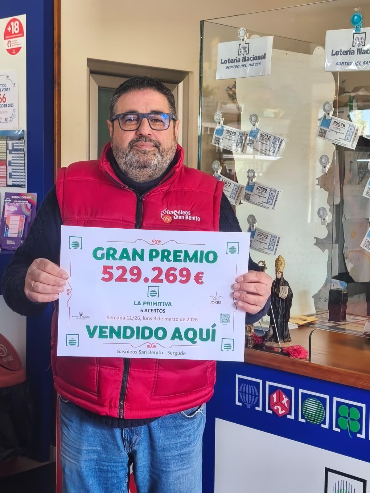 Juan Loureiro posa orgulloso con el cartel del premio de más de medio millón de euros repartido en su punto de venta de Gasóleos San Benito, en Boqueixón