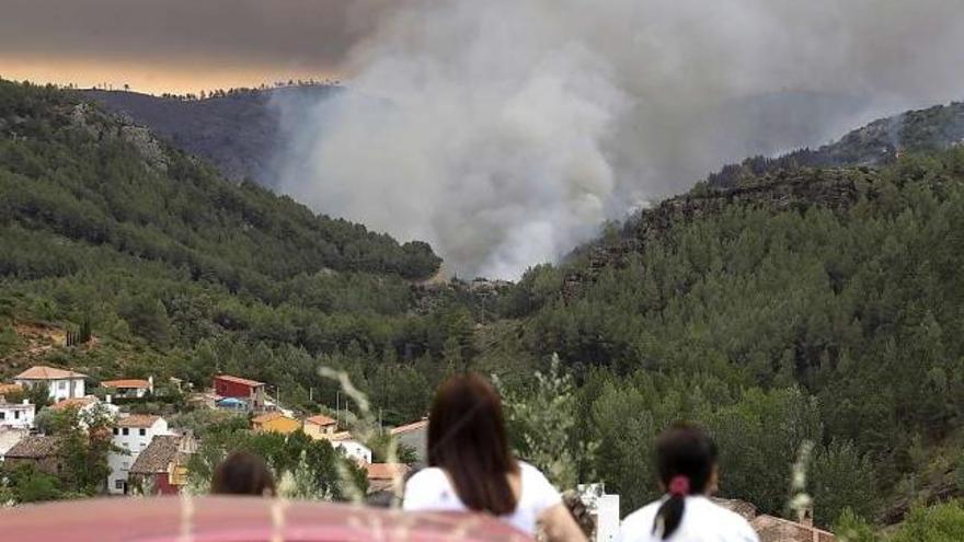 Varias personas observan el incendio en la localidad castellonense de Bejís.