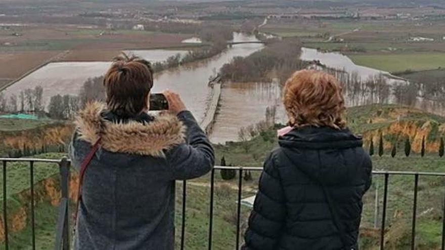 Dos mujeres contemplan desde el mirador del Espolón el pago conocido como La Bardada en el que el agua anegó fincas, caminos y los paseos fluviales.