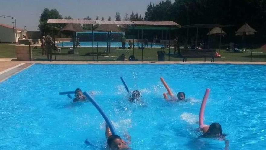 Un grupo de pequeños bañistas disfruta de una actividad en la piscina de verano.