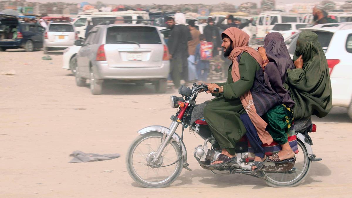 Una motocicleta con tres pasajeros cruza la frontera entre Afganistán y Pakistán.