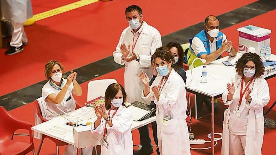 Trabajadores sanitarios aplauden en el interior del hospital de campaña de Ifema durante la visita de Díaz Ayuso.